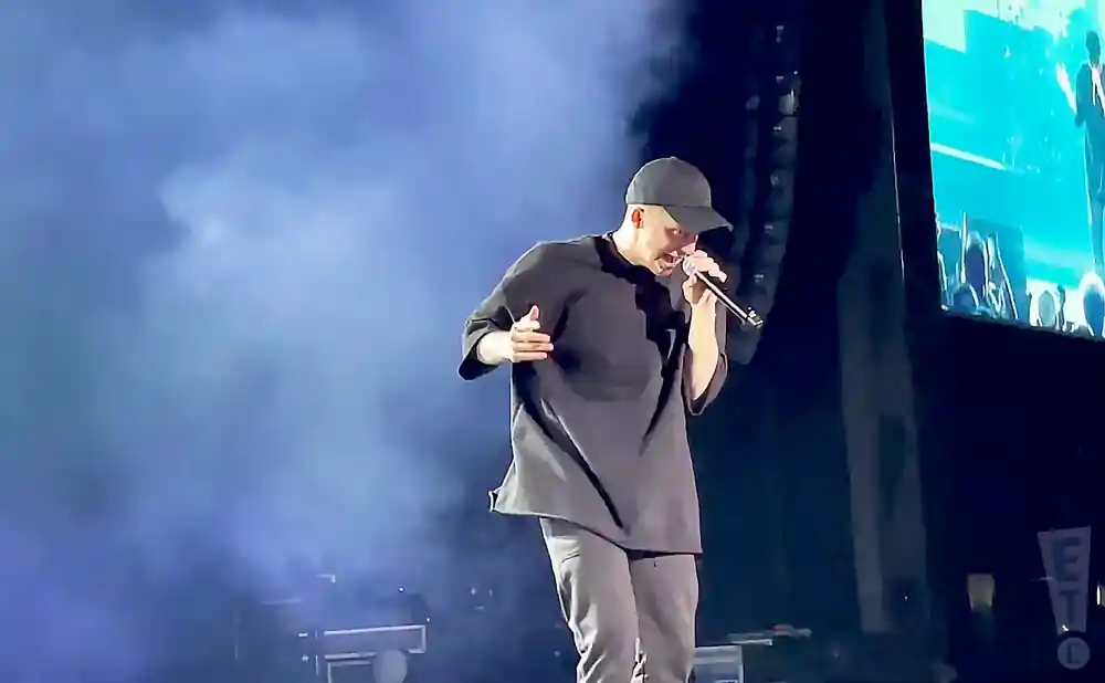 nf performing on stage in a black tshirt and hat