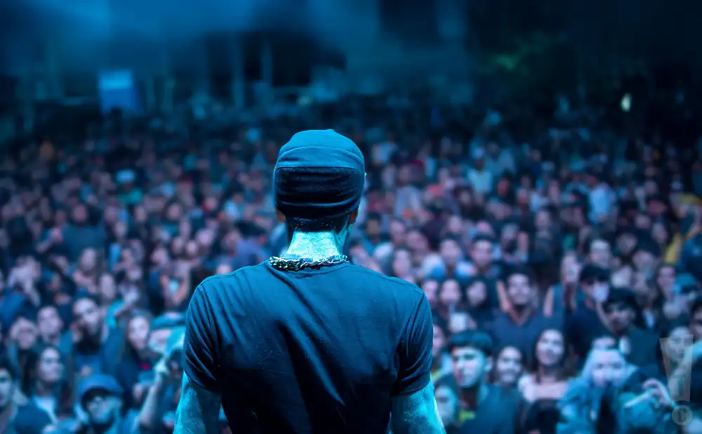 a rear view photo of dirty snatcha performing a concert on stage to a lively audience