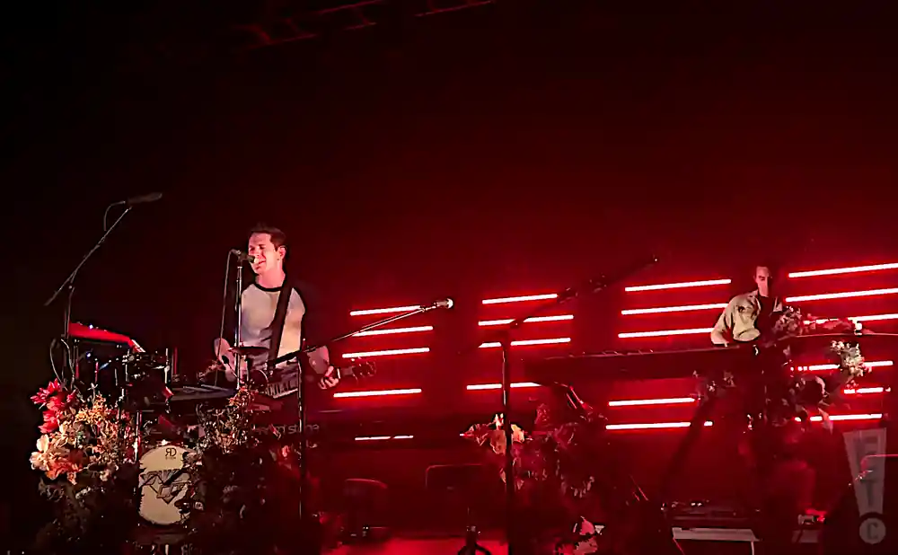 owl city performing on stage in front of red lights