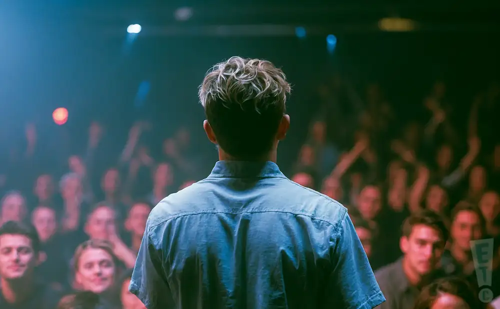 a rear view photo of connor price performing a concert on stage to a lively audience