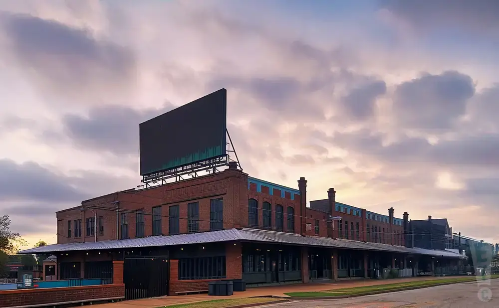 Brick building with a large billboard against a cloudy sky.