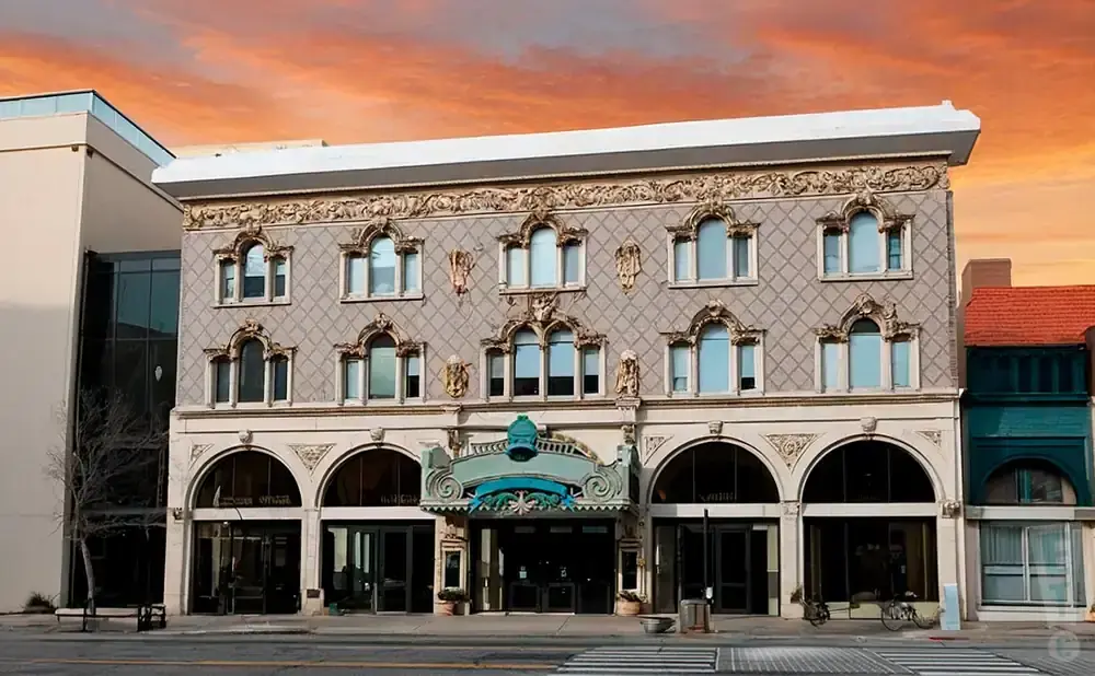 Exterior of an ornate historic building with arched windows and decorative facade, under a vibrant sunset sky.