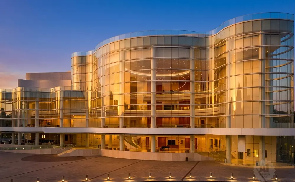 A modern glass building with a curved facade reflecting the warm glow of sunset.