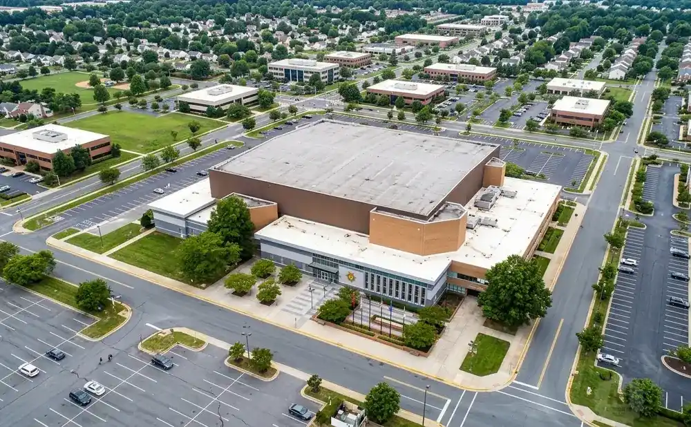Aerial view of a large building complex with parking lots and surrounding greenery.