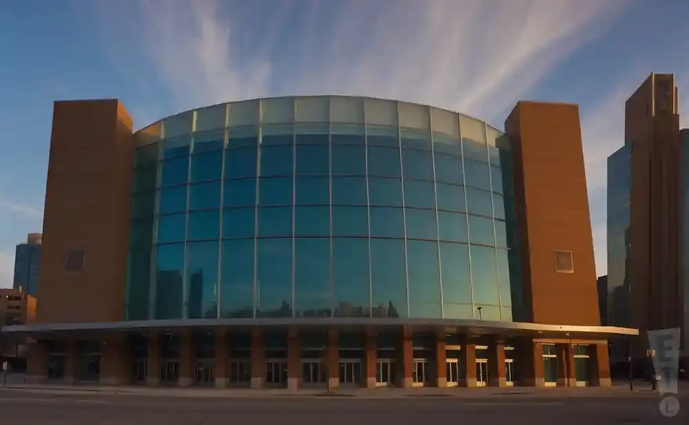 A modern glass and brick building with a curved facade under a cloudy sky.
