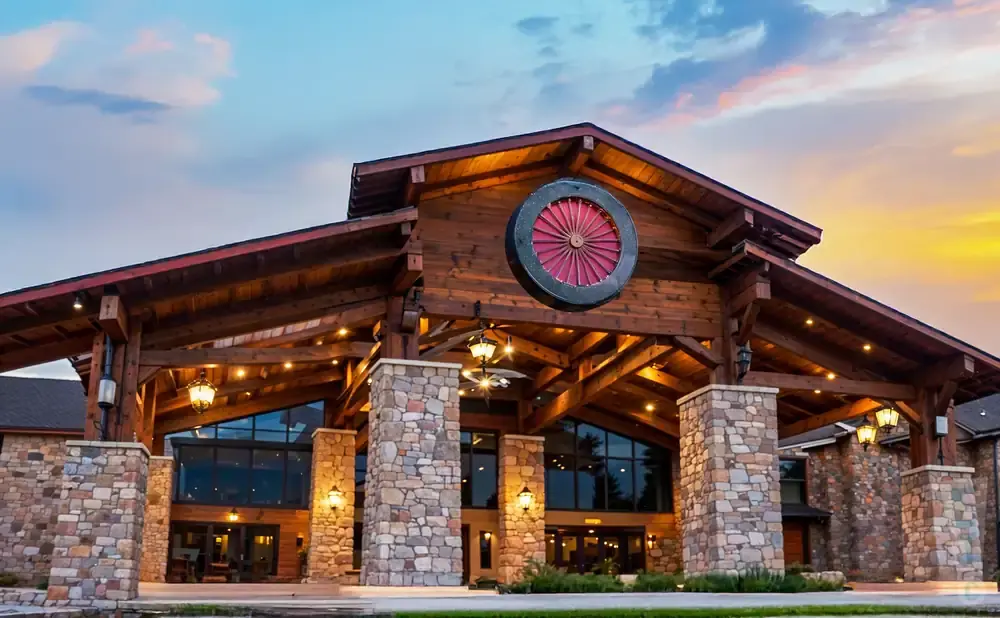 Rustic lodge entrance with stone pillars and a large wagon wheel decoration.