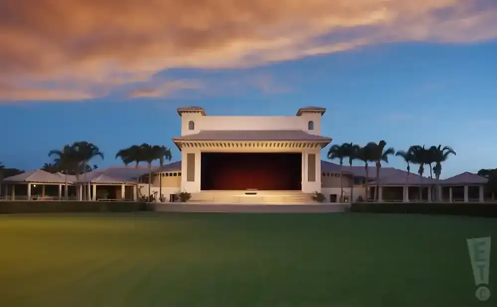 An open-air amphitheater with palm trees at sunset.