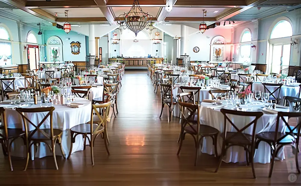 A formal dining room set up for a banquet or wedding reception with round tables and chairs.