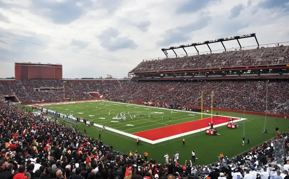 A football game in a packed stadium under a cloudy sky.