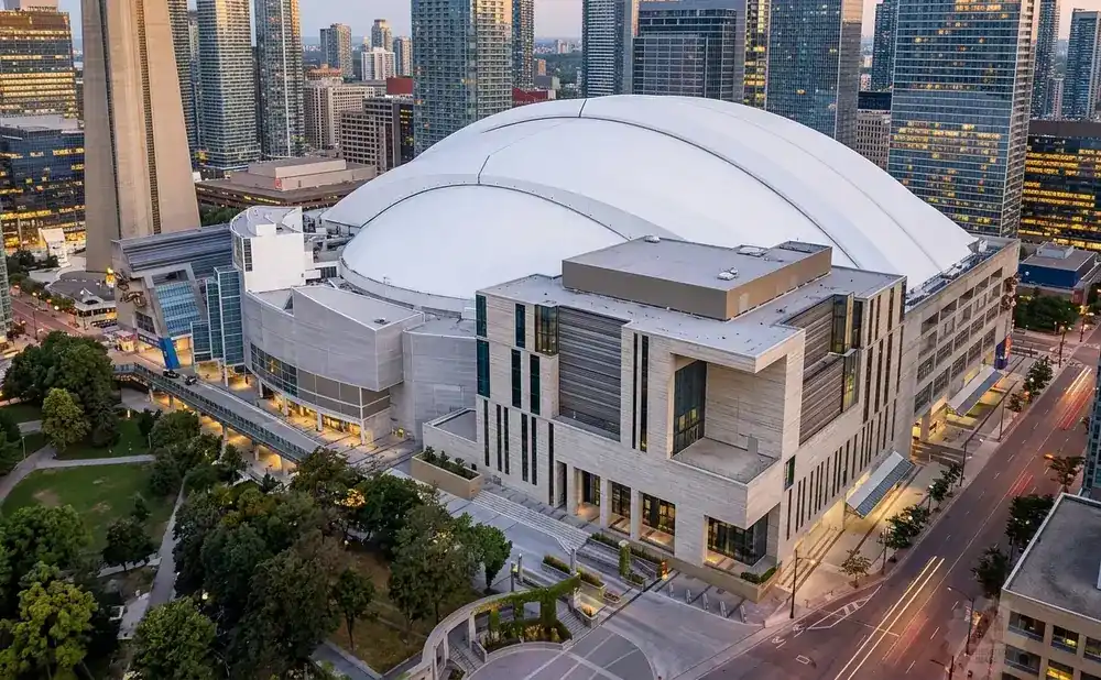 Aerial view of the Rogers Centre stadium and surrounding Toronto skyscrapers at dusk.