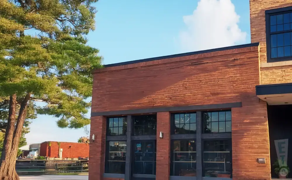 Exterior of a brick building with large windows and a tree.