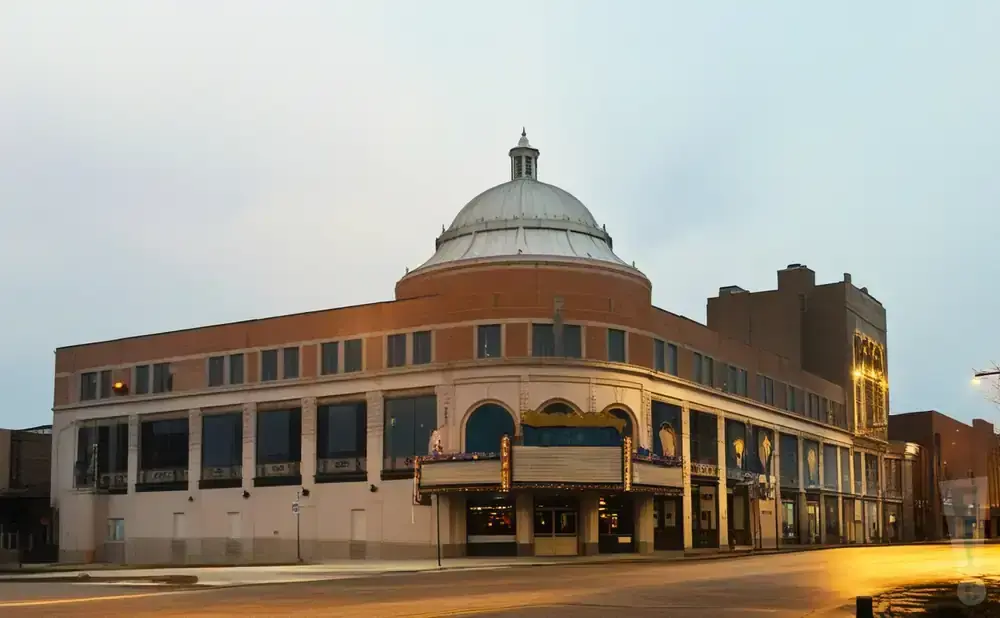 A large, domed building with a marquee and a street in front.