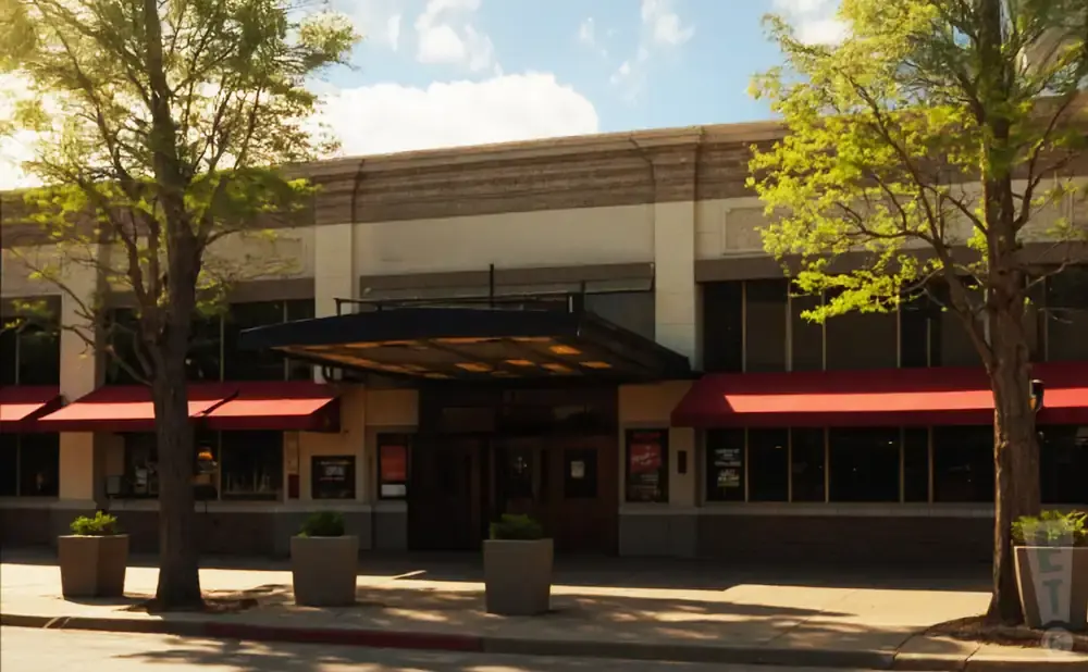 Exterior of a building with red awnings over windows and a covered entrance.