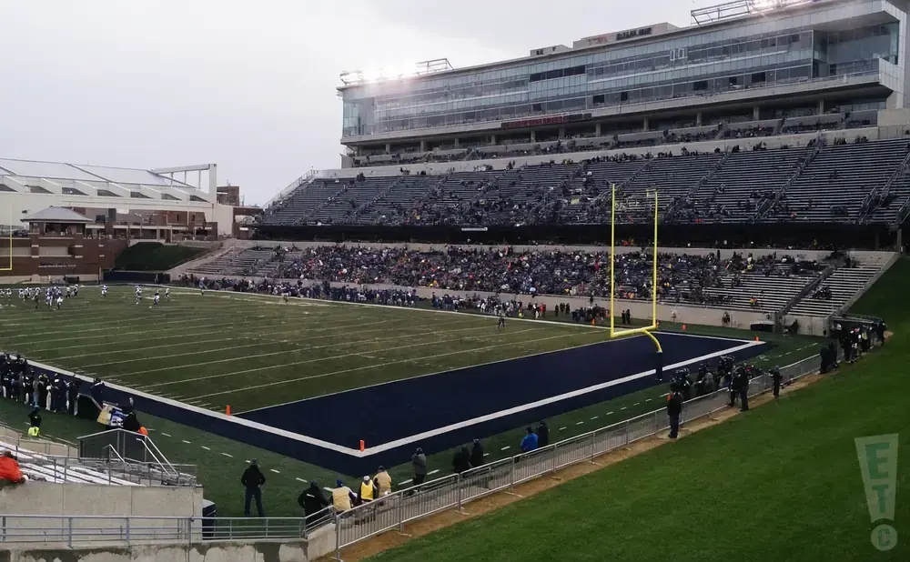 An American football stadium with a game in progress and a mostly full crowd.