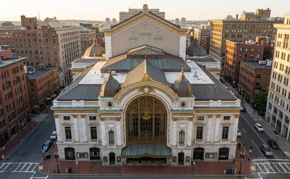 An aerial view of a grand, ornate theater with copper domes, golden detailing, and a large arched entryway.