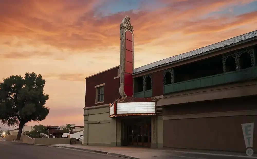 Marquee of an old theater glows under a colorful sunset sky.