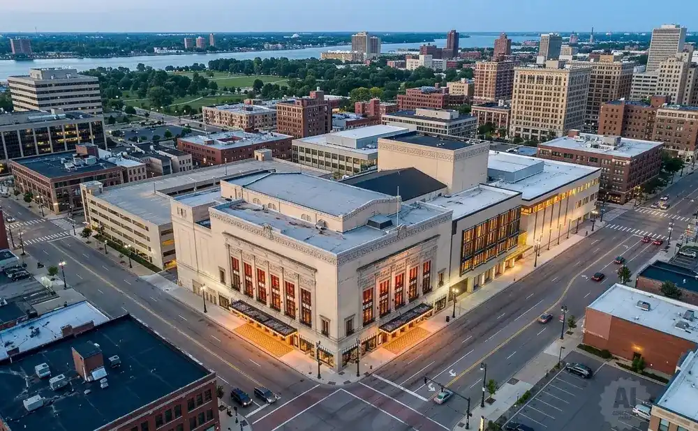 Aerial view of a city street with a large, ornate theater in the foreground, surrounded by brick and modern buildings.