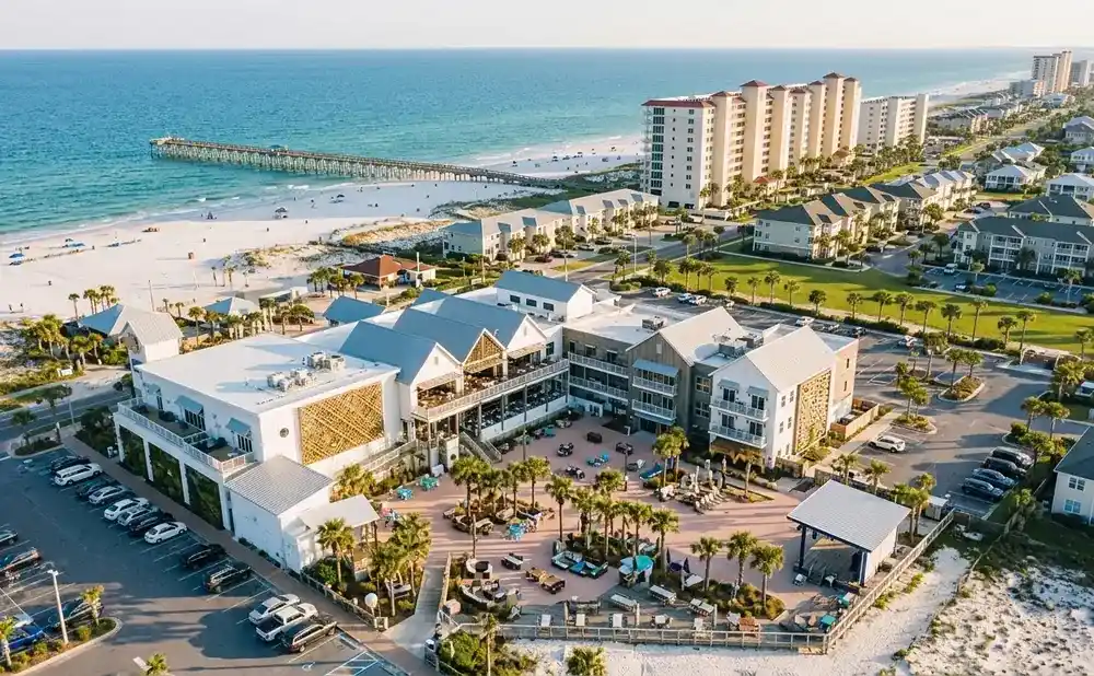 Aerial view of a resort town with hotels, condos, a pier, and a beach.