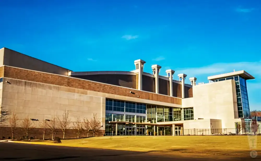 Modern convention center with large glass windows and light-colored stone facade under a clear blue sky.
