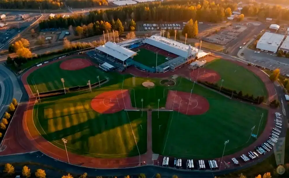 Aerial view of a baseball stadium and fields at sunset.