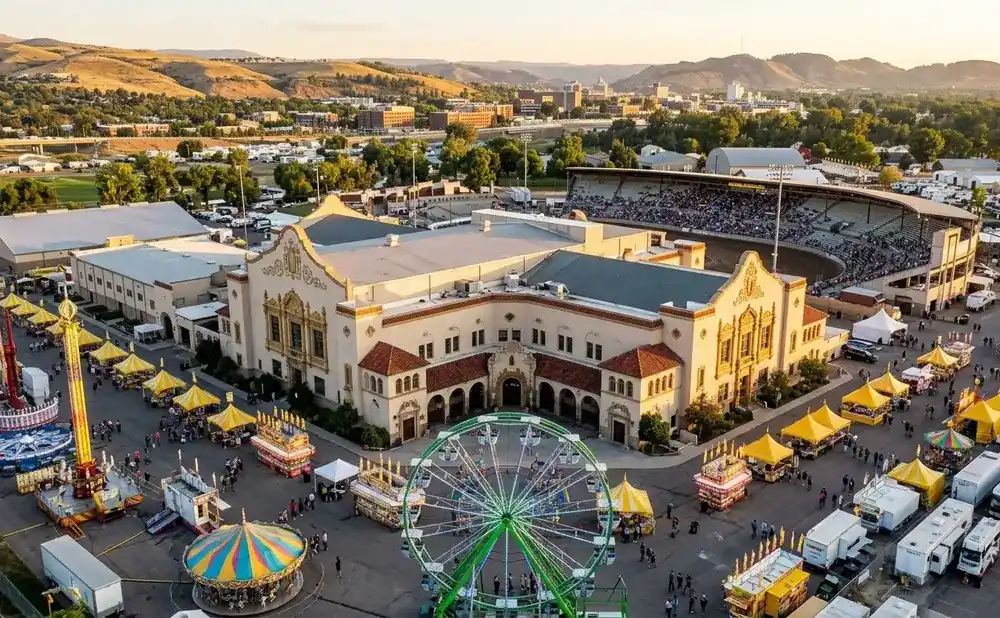 Aerial view of a fair with rides, food booths, and a stadium filled with spectators.