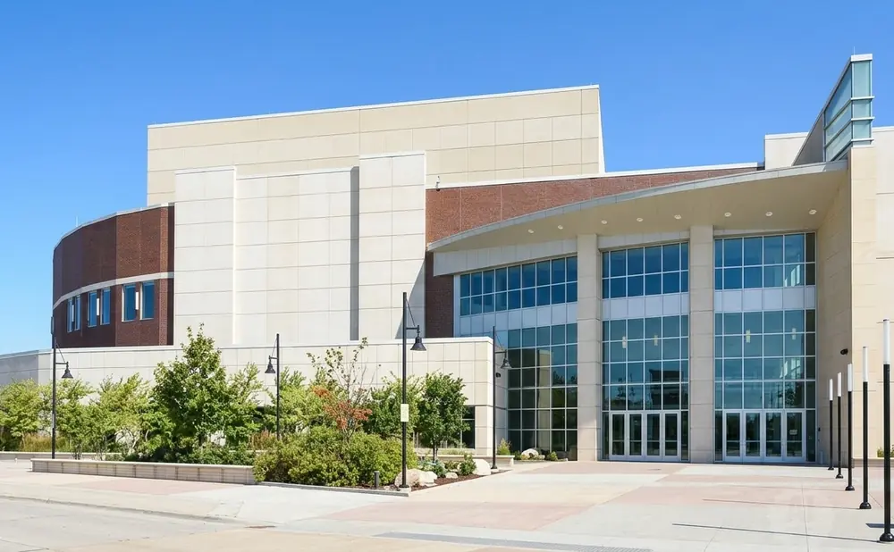 Modern building with large glass windows and brick accents, set against a clear blue sky.