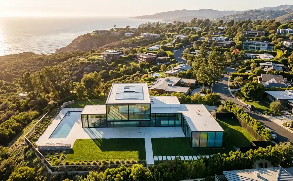 Modern glass house with pool overlooks the ocean and lush hillside homes.