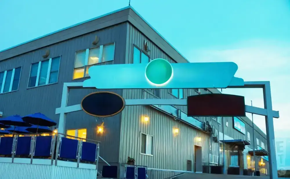 A building with a blue sign and a green circle under a cloudy sky.