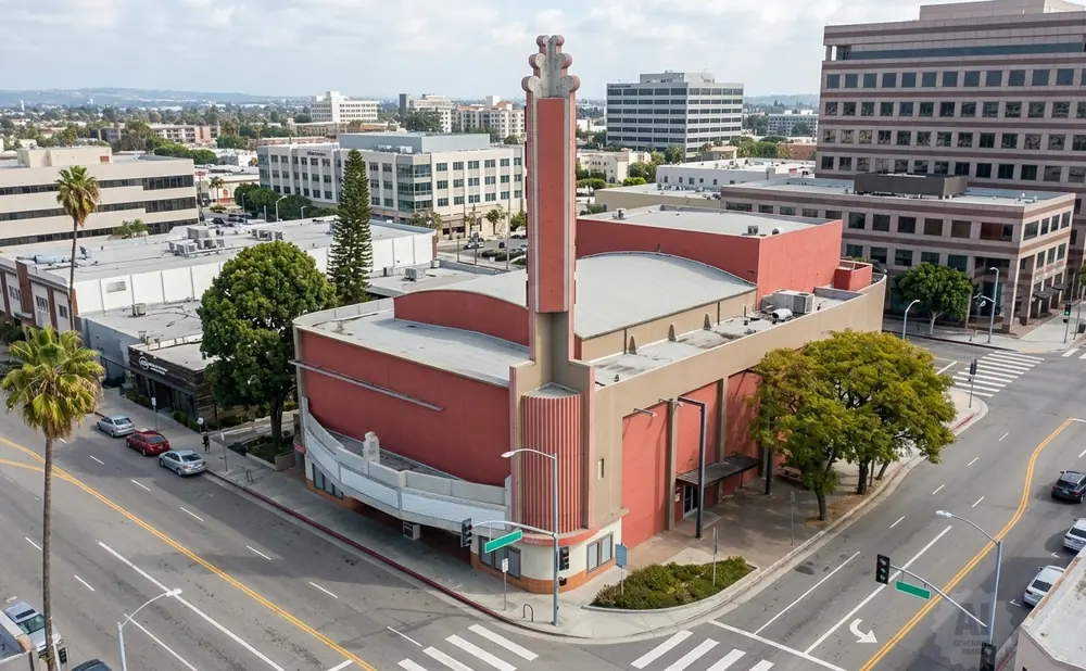 An aerial view of a red building with a tall, decorative tower at a street corner.
