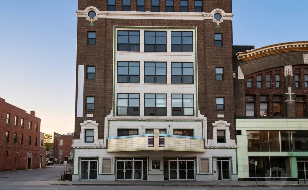 Exterior of an old theater with a marquee, brick facade, and large windows.