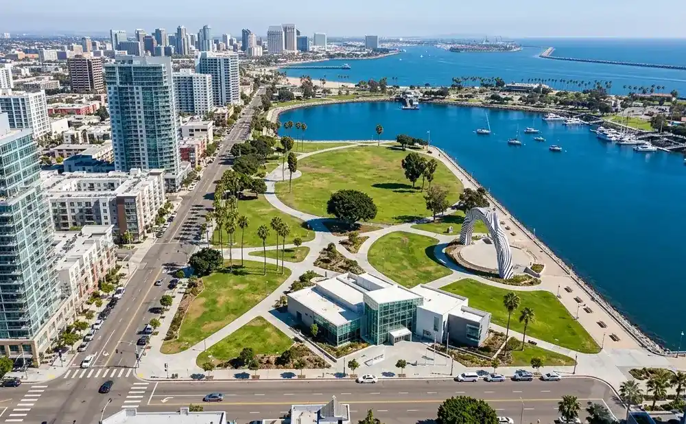 Aerial view of San Diego Bay, with boats, a park, and modern buildings.