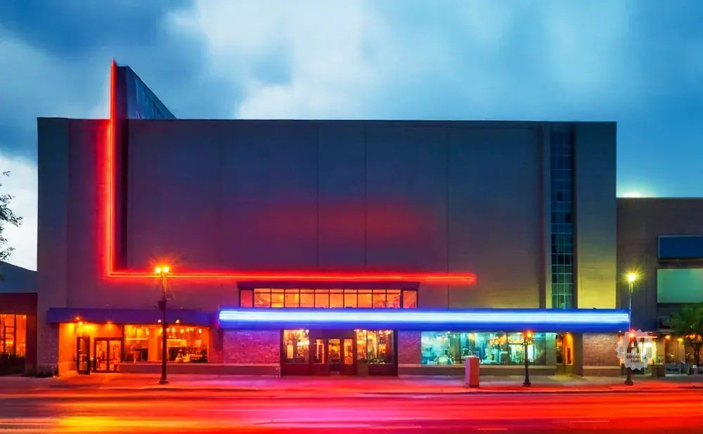 Modern theater with bright red and blue neon lights at dusk.