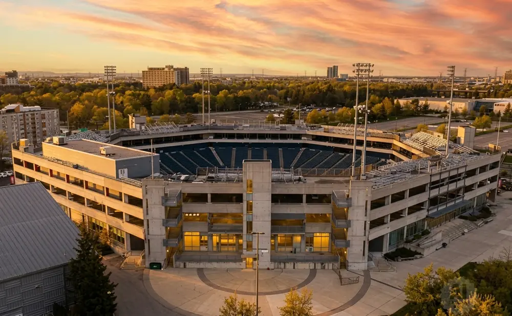 Aerial view of a stadium and parking garage at sunset.
