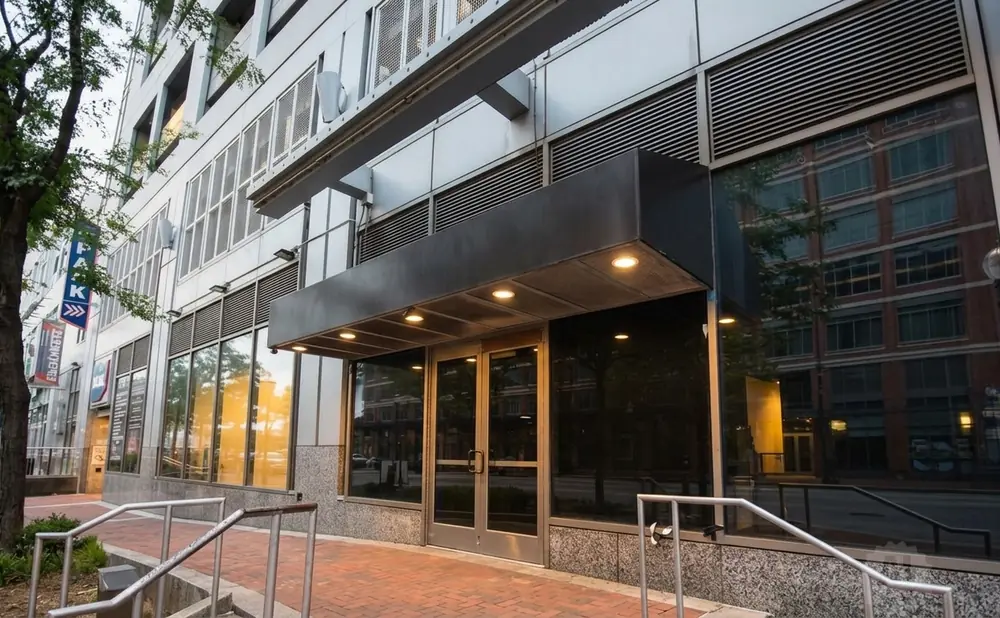 Modern building facade with glass doors and windows reflecting an adjacent brick building.