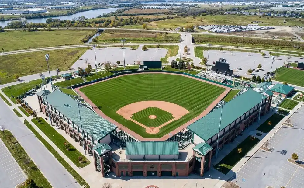 Aerial view of a baseball stadium and surrounding fields on a sunny day.