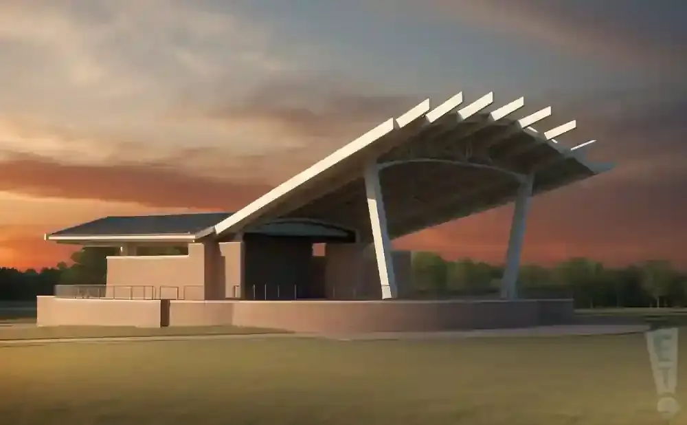 An amphitheater with a modern, sloped roof against a dramatic sunset sky.
