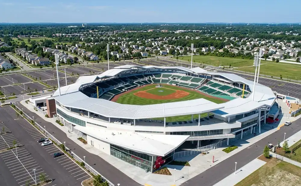 Aerial view of a modern baseball stadium with green seats, a baseball field, and surrounding neighborhoods.