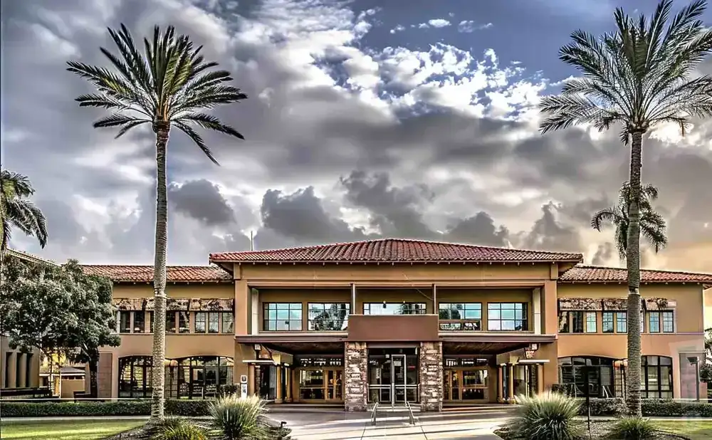 A building with palm trees and a cloudy sky.