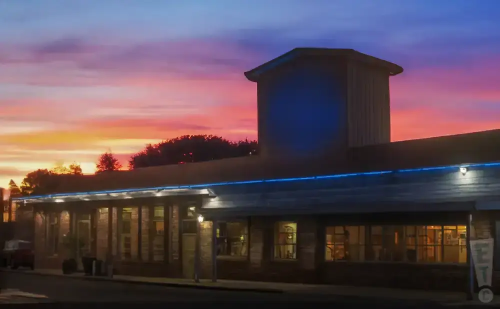 A building with blue lights along the roof at sunset.