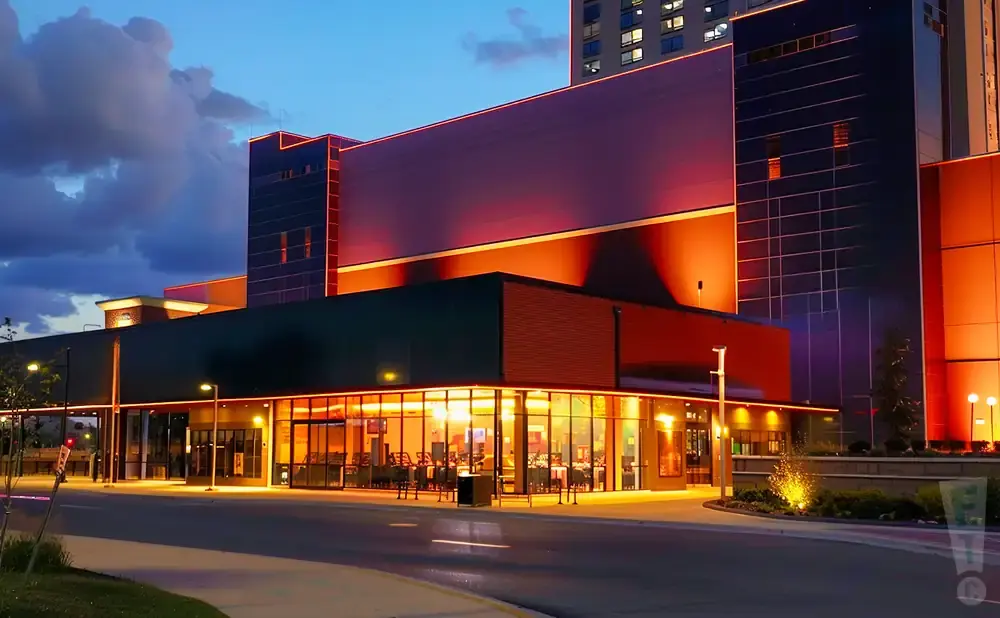Modern building illuminated at dusk with warm lighting and contrasting dark facades.