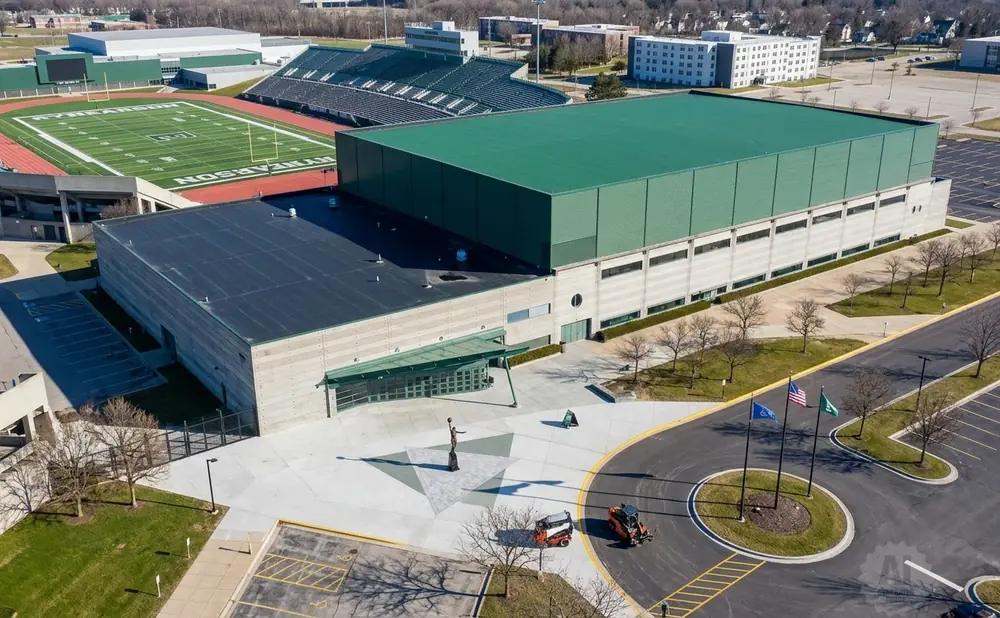 Aerial view of a large indoor athletic facility next to a football stadium with a track.