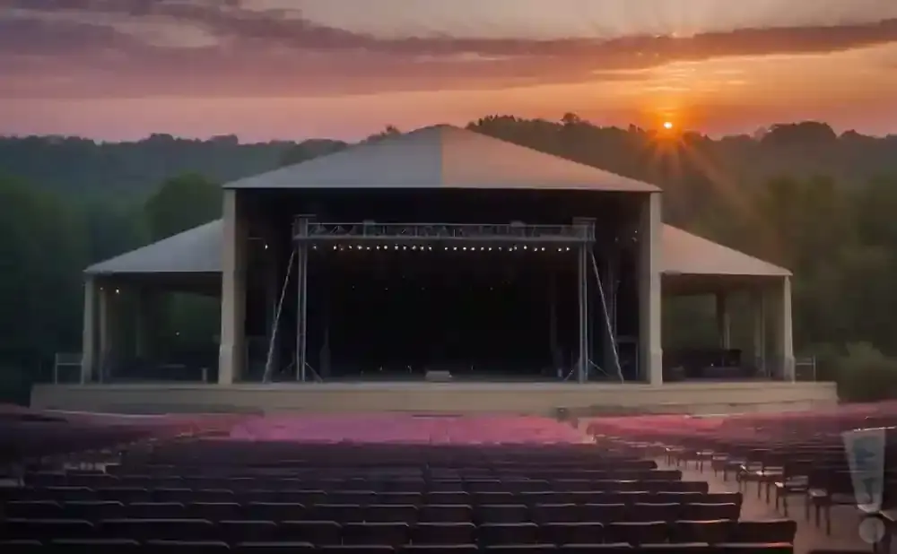 An outdoor amphitheater stage at sunset with rows of empty seats.