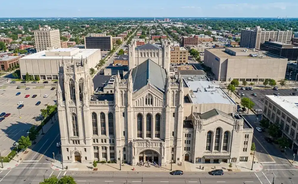 Aerial view of a large Gothic-style stone building with intricate details, set against a city skyline.