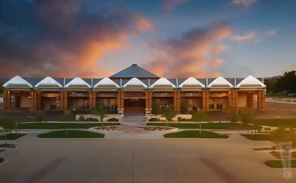 Modern building with peaked roof sections under a colorful sunset sky.