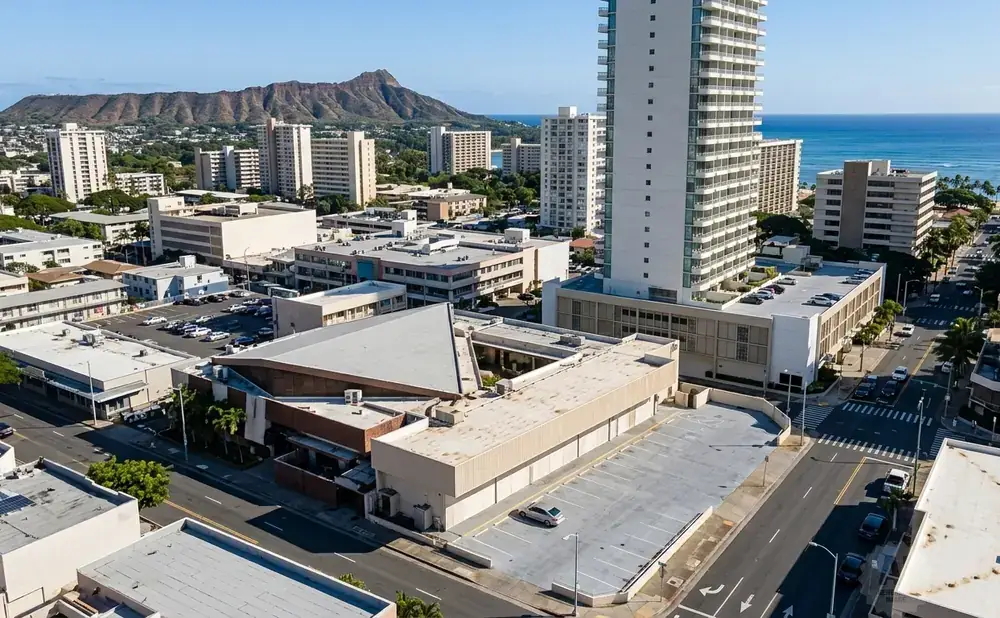 Aerial view of a city with tall buildings, a mountain, and the ocean in the background.