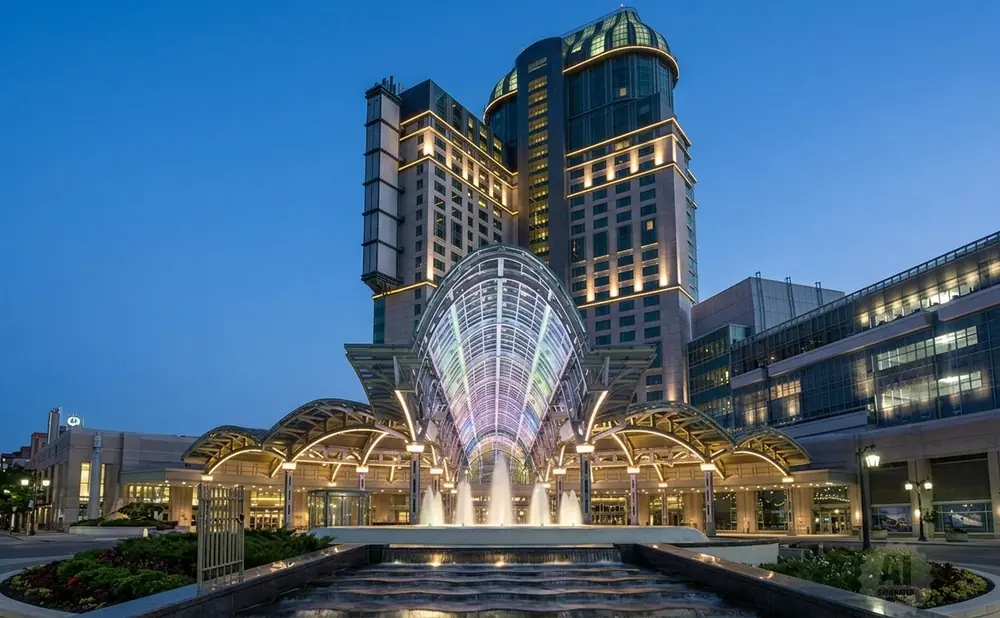 A grand hotel with a colorful glass entrance and a fountain at dusk.