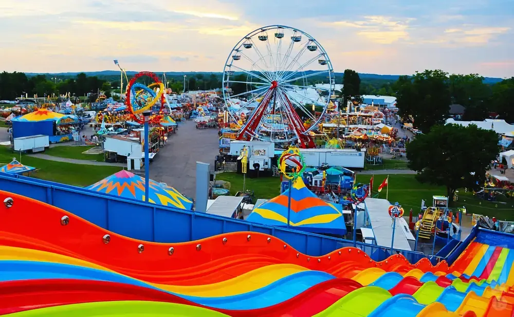 An aerial view of a bustling amusement park with a Ferris wheel, colorful slides, and various rides.