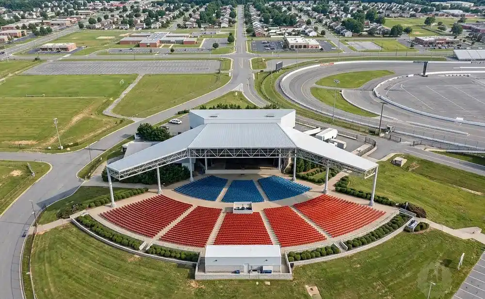 Aerial view of an outdoor amphitheater with a stage and red and blue tiered seating.