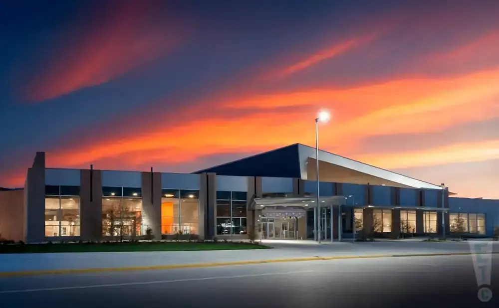 Modern building with large windows and a dramatic sunset sky.