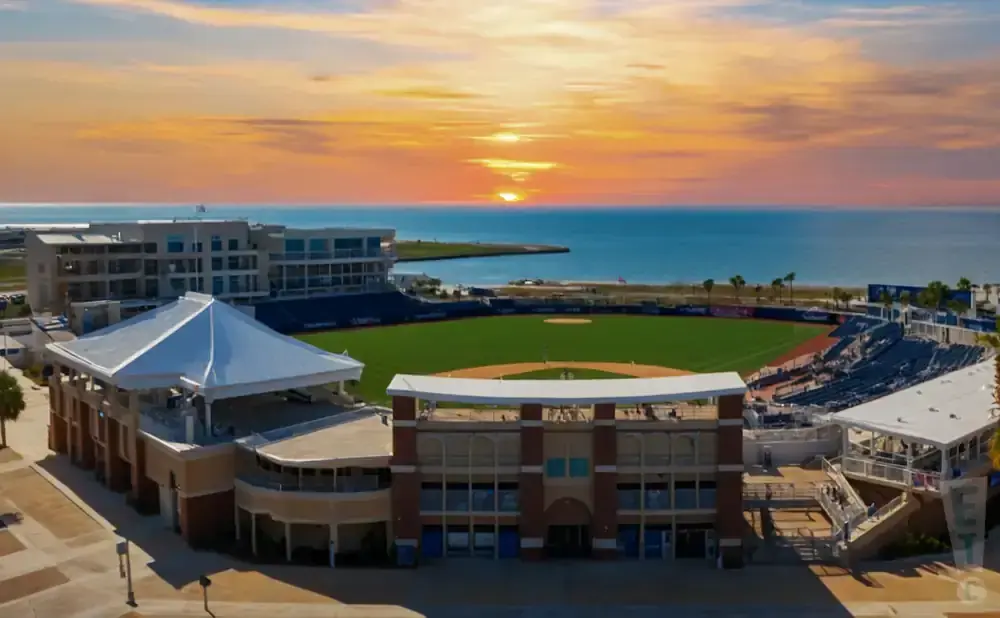 Aerial view of a baseball stadium at sunset with the ocean in the background.